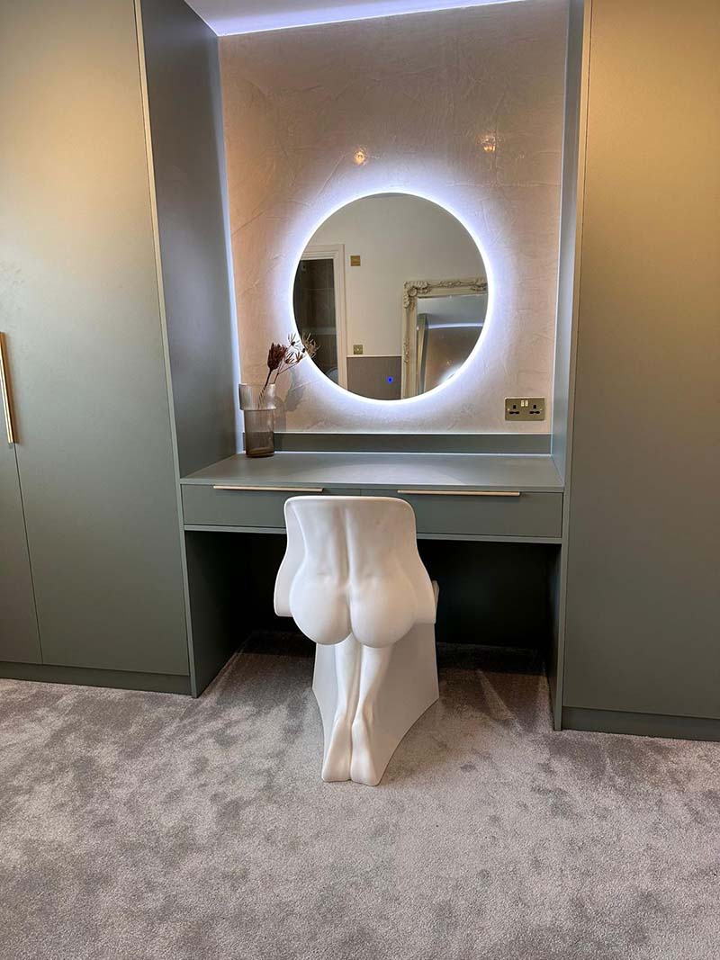 a picture of a bespoke dressing table in a bedroom dressing area, with a large mirror on the wall.